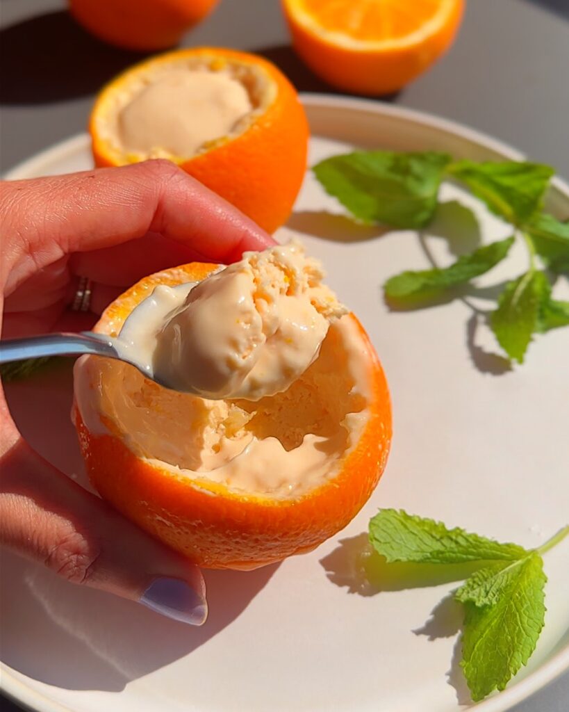 Aperol spritz ice cream in orange cups on a plate with mint leaves