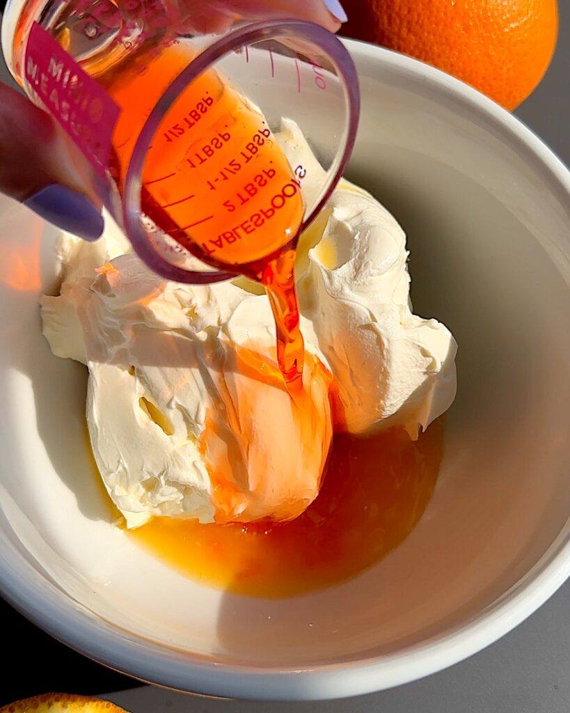 Aperol poured over cream cheese in a bowl.