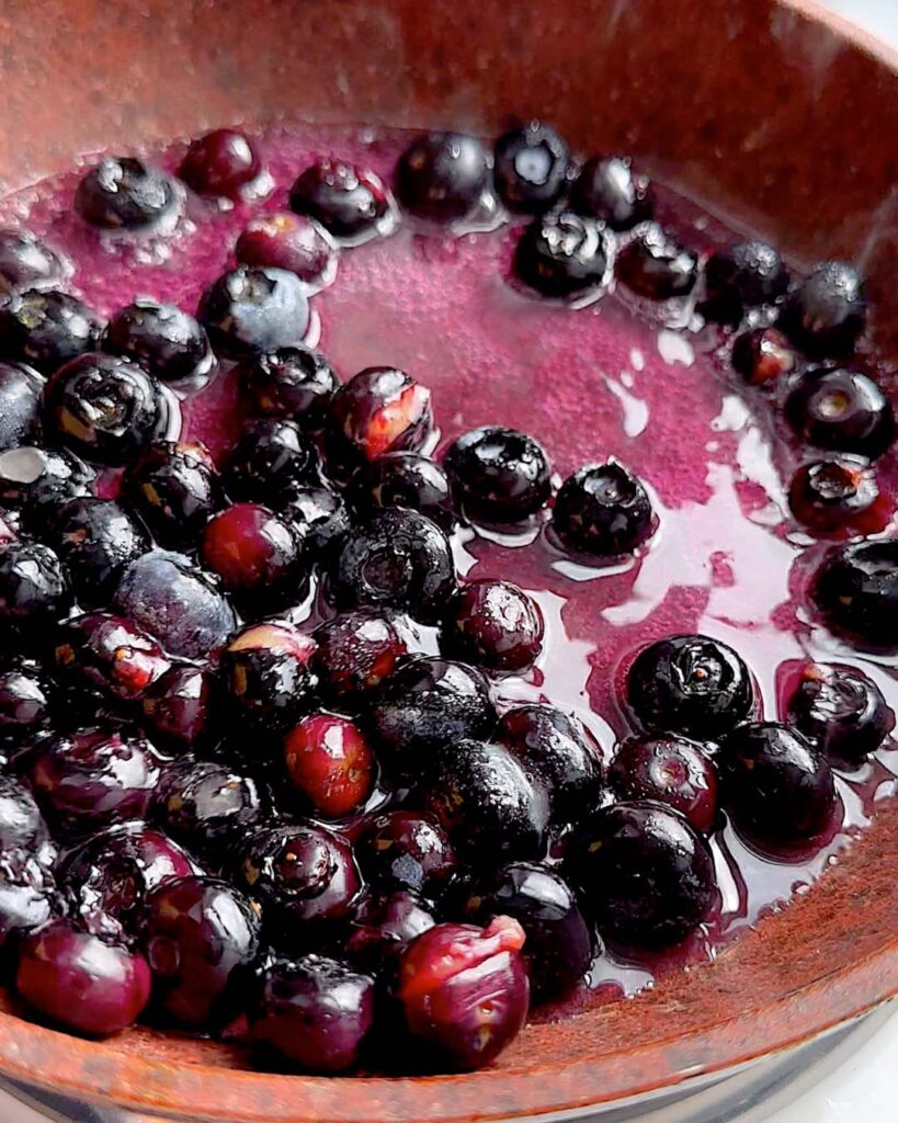 Blueberry sauce being cooked in a saucepan.