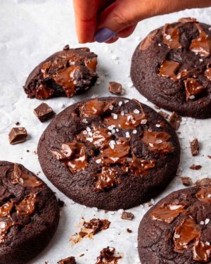 Cracked sea salt being sprinkled over chocolate brownie cookies.