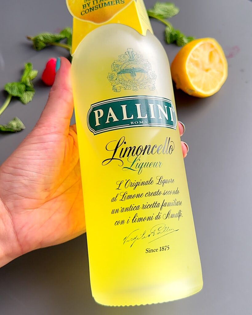 A bottle of Limoncello held in a lady's hand.