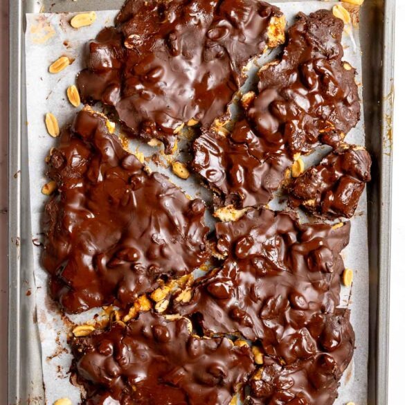 Snickers chocolate bark broken into pieces on a baking tray.