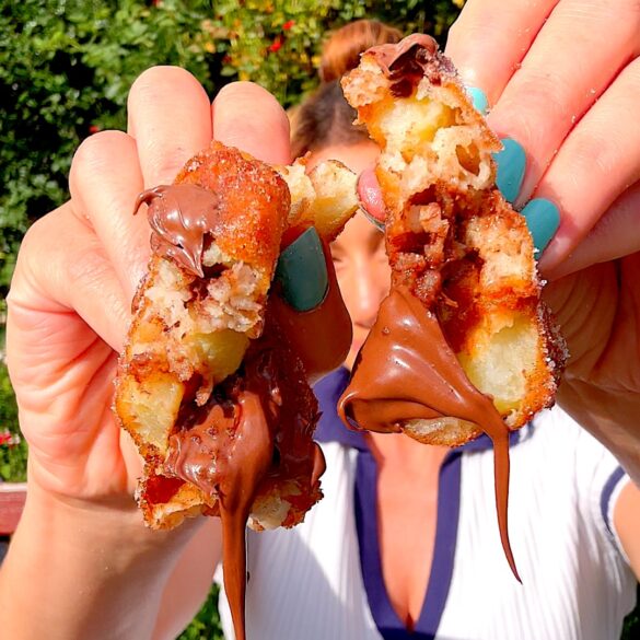 Nutella stuffed apple fritter torn in half with Nutella dripping down.