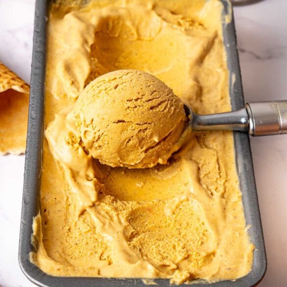 Pumpkin spice latte ice cream being scooped in its container.