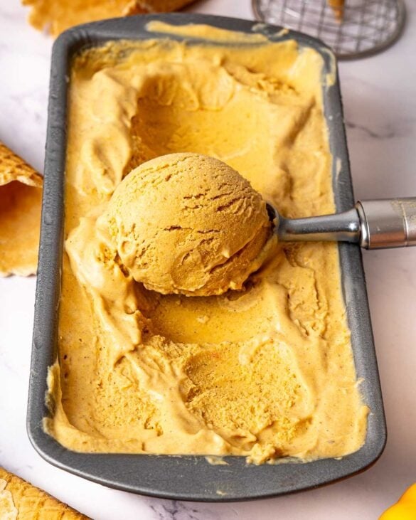 Pumpkin spice latte ice cream being scooped in its container.