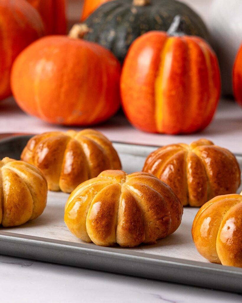 Pumpkin shaped buns on a baking tray.