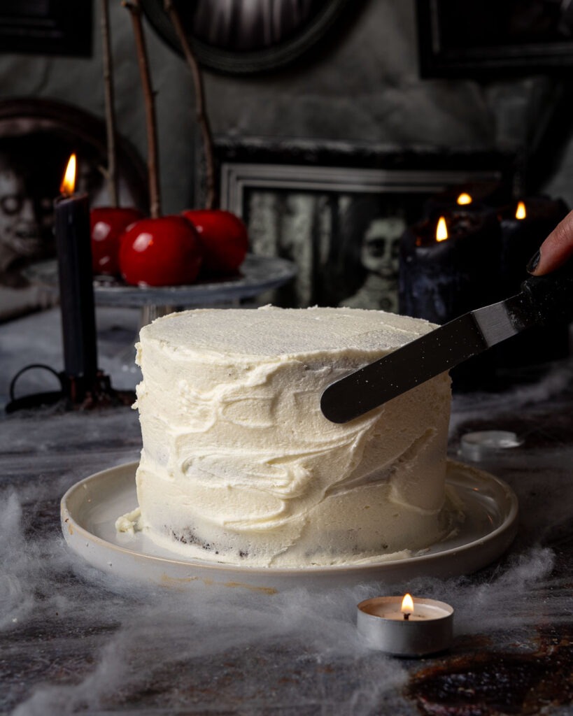 Vanilla icing being spread over a cake.