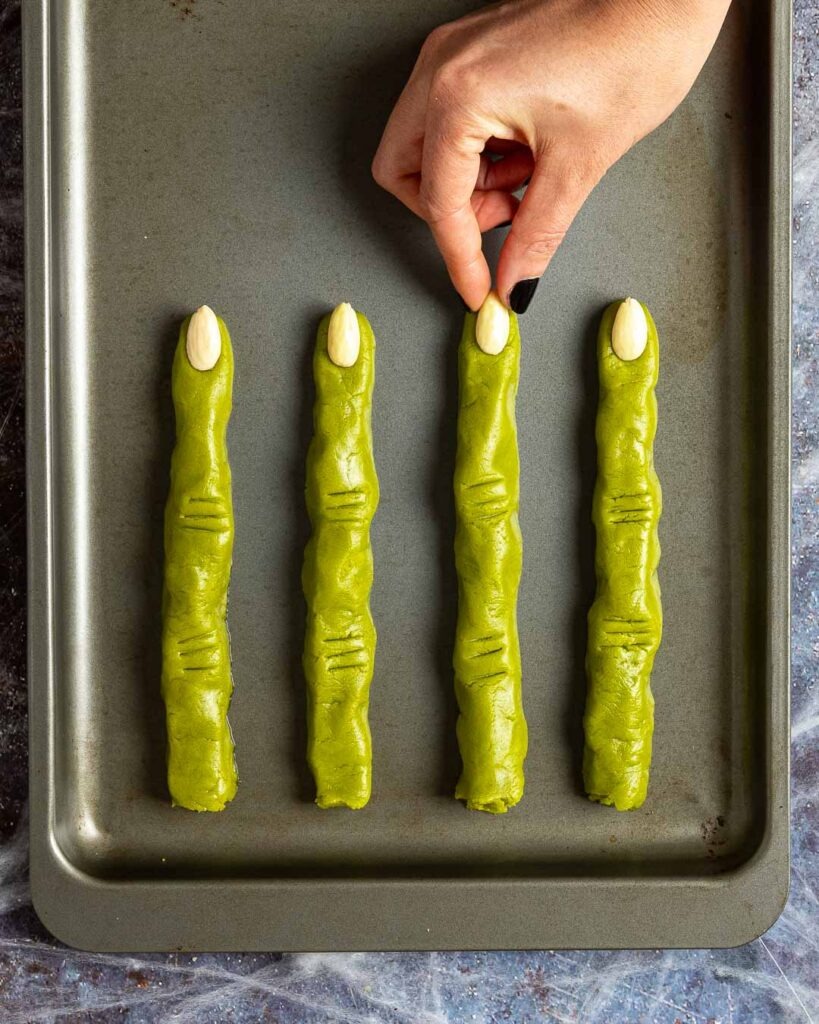 Green witch finger cookies on a baking tray.