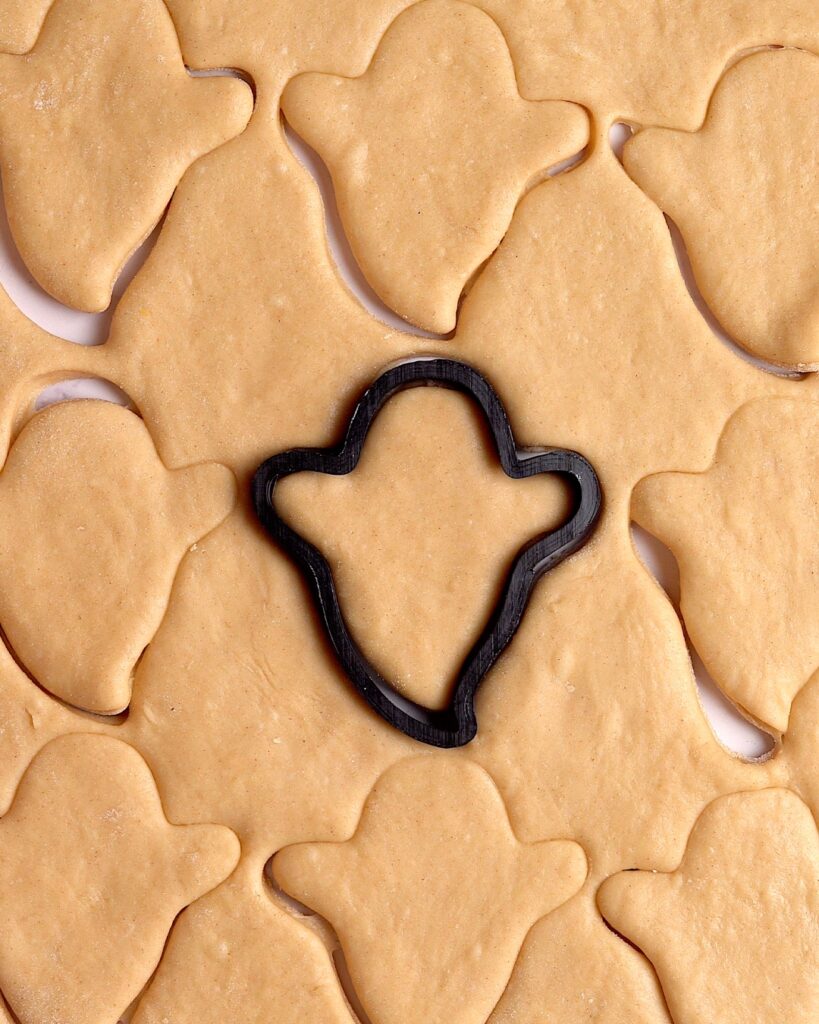 Ghost cookie cutter making ghost shapes in beignet dough.