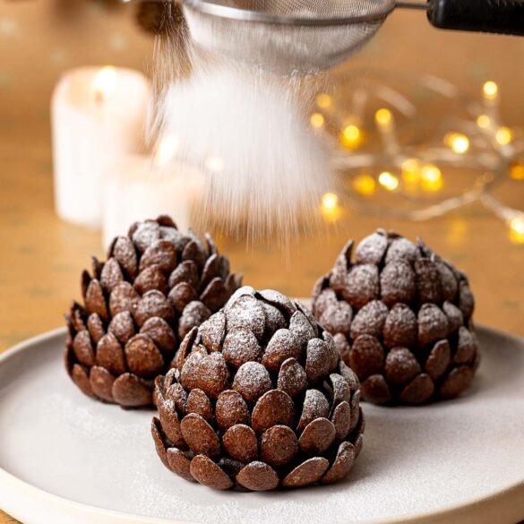 Brownie pine cones being dusted with icing sugar.