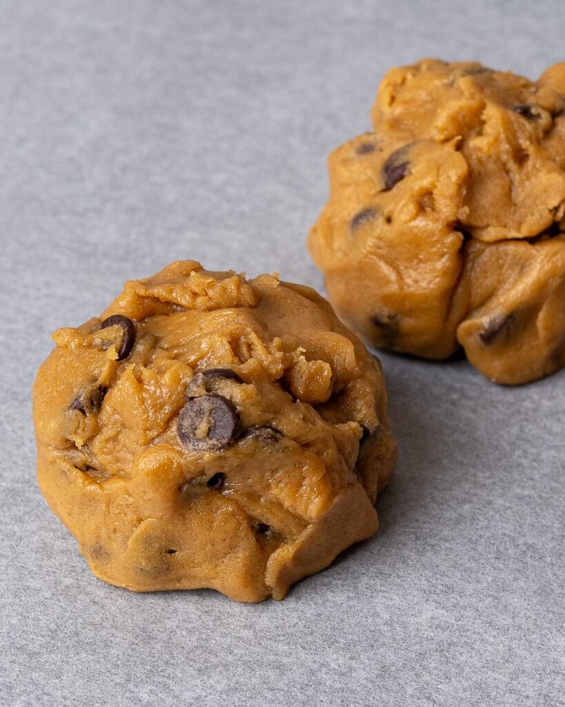 Cookie dough balls on a baking tray before being baked in the oven.