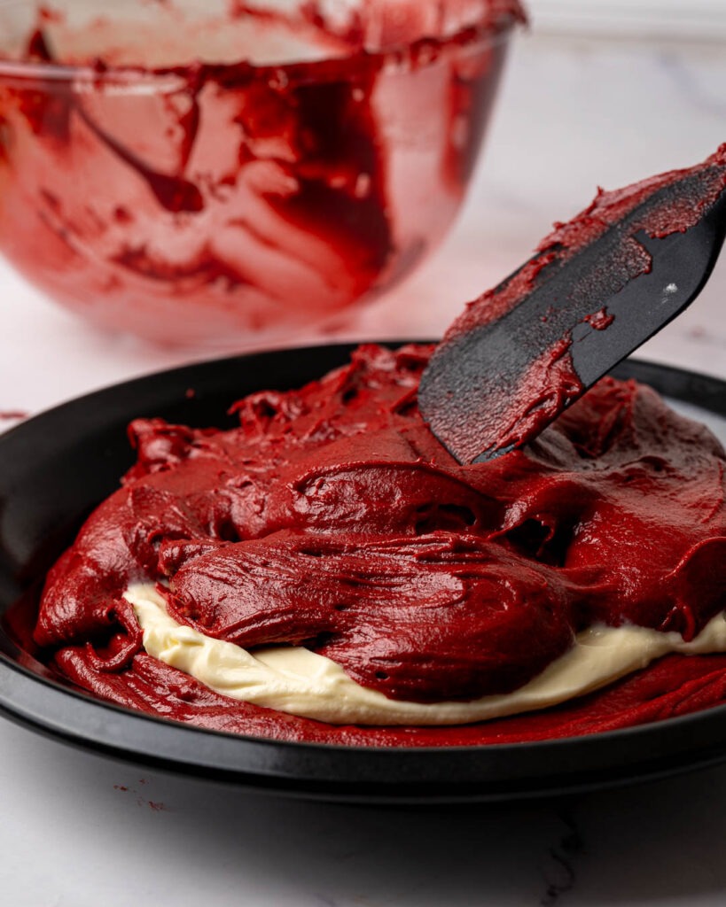 Red velvet brownie being added to a pie dish.