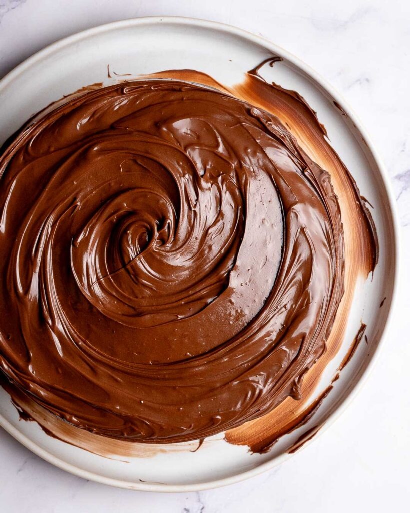 A top down picture of a chocolate cake covered on Nutella.