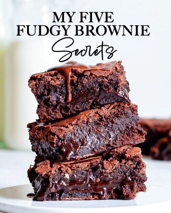 A stack of three fudgy brownies with a chocolate dripping running down.