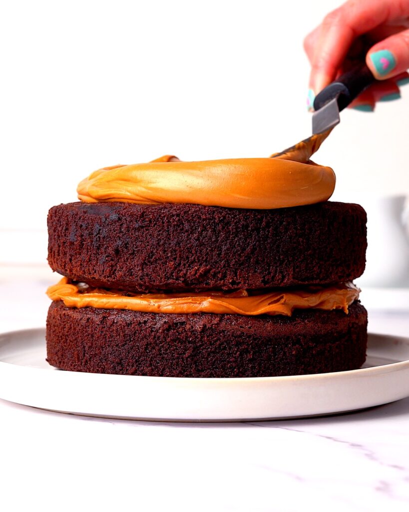 Biscoff being spread on a chocolate cake