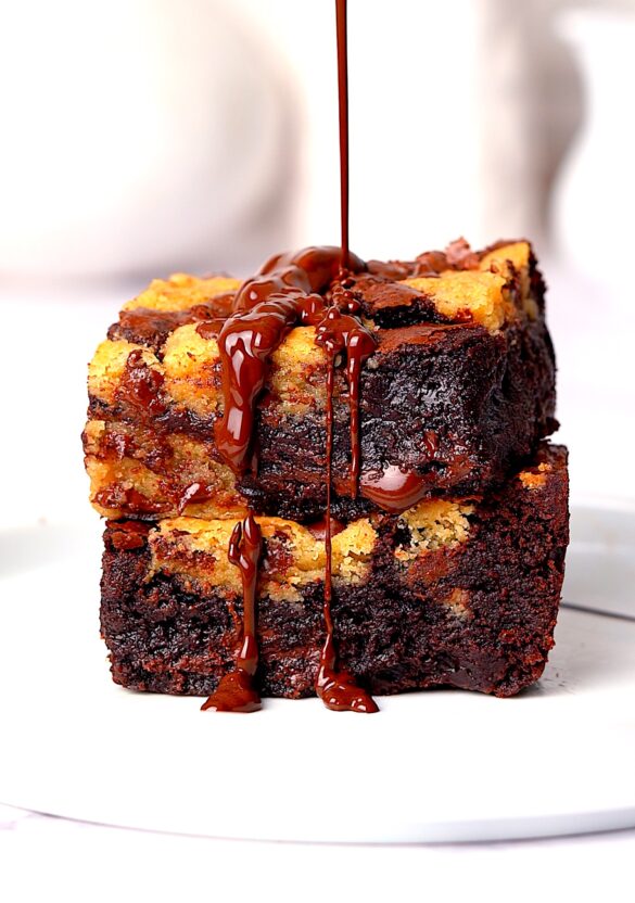 Brookies stacked on top of each other with chocolate being drizzled on top.