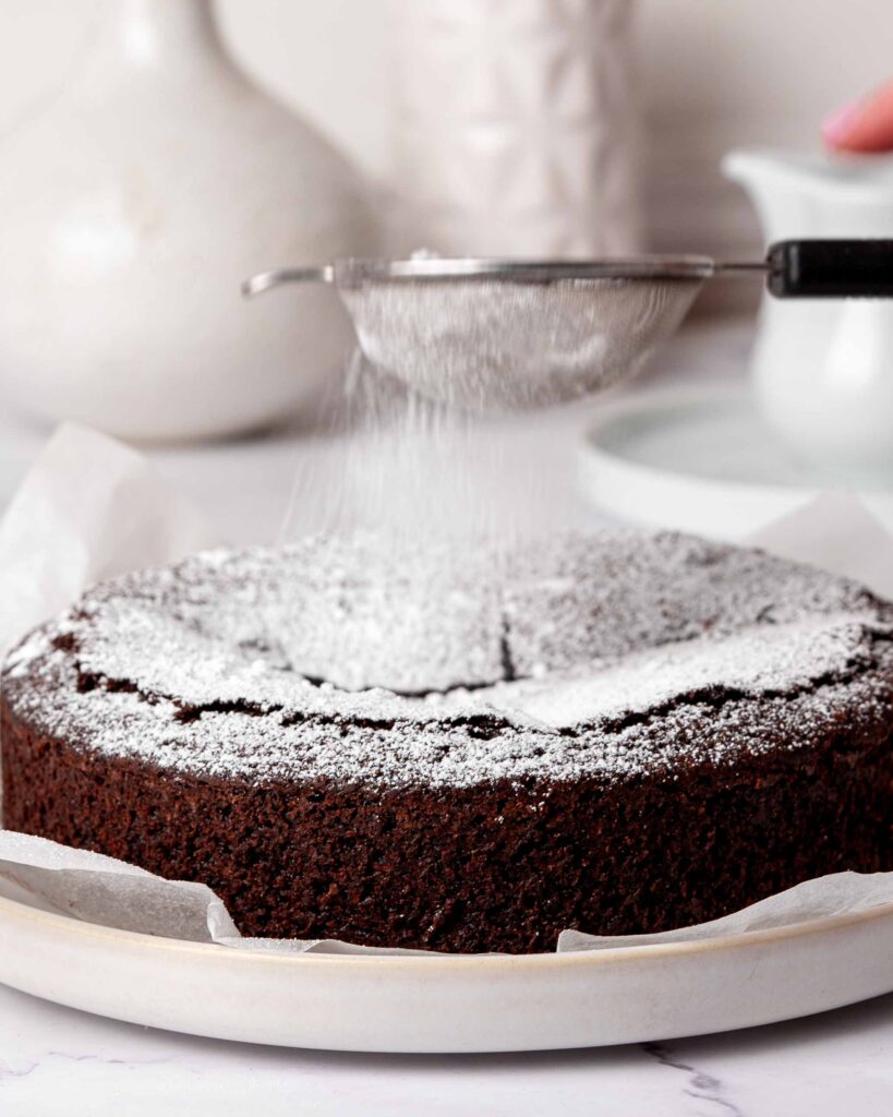 Kladdkaka being dusted with icing sugar.
