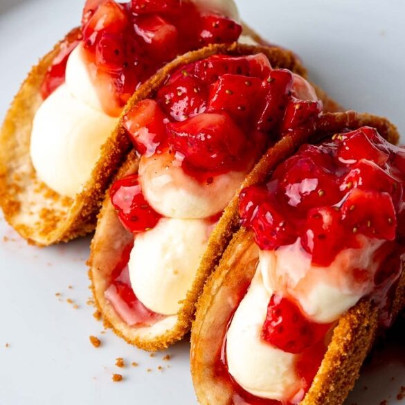 Three strawberry cheesecake tacos on a plate.