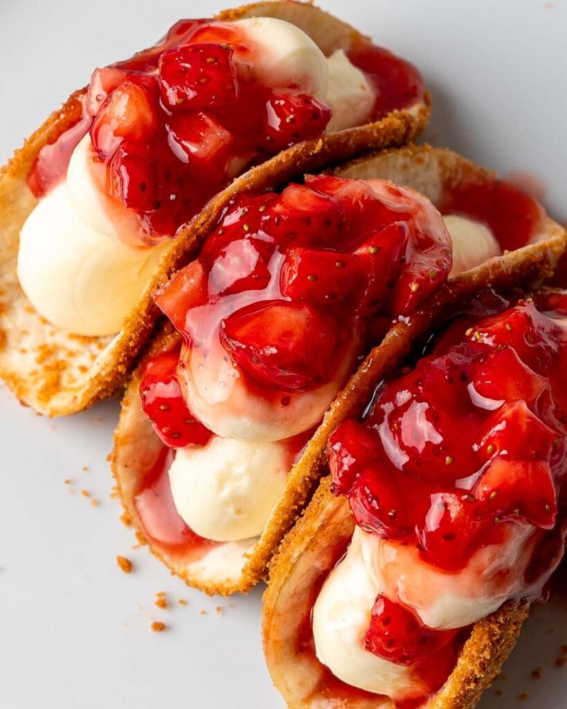 Three Strawberry cheesecake tacos on a plate.