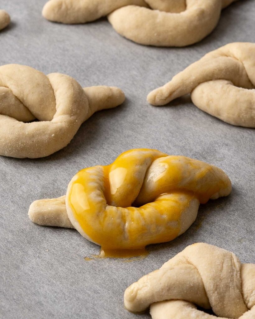 Pretzel knot on a baking tray with egg wash.
