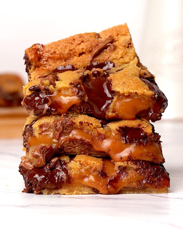 A stack of three gooey caramel chocolate chip cookie bars.