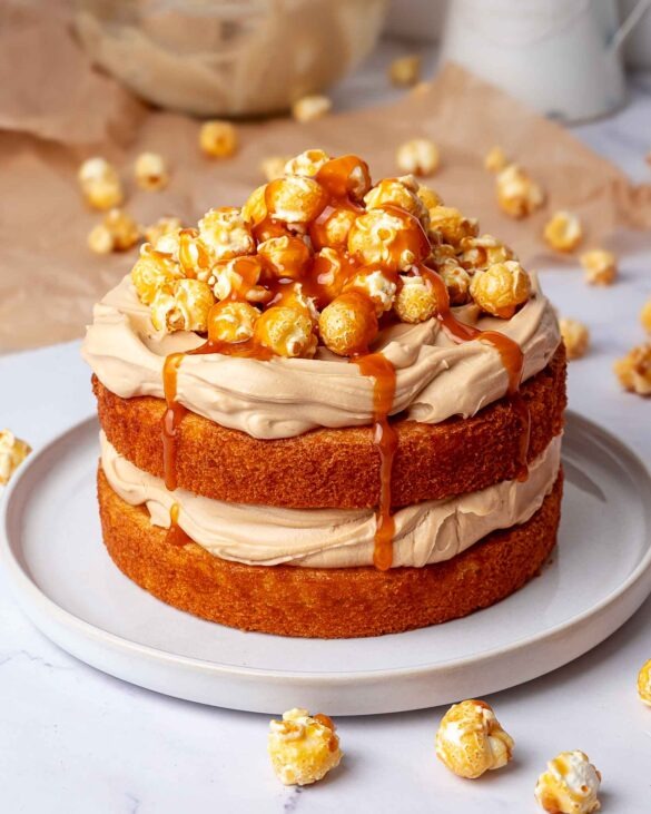 Salted caramel latte cake with popcorn on top and Carmel sauce running down.