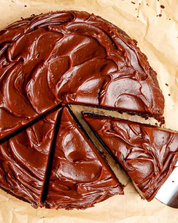 Image of the top of a Chocolate cake with chocolate ganache on top with three slices cut into it.