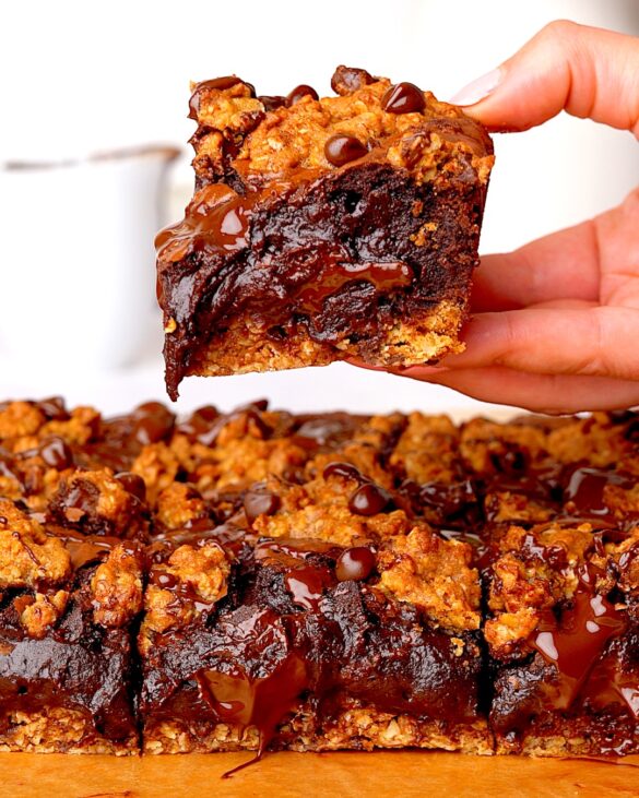 Chocolate chip oatmeal brookies being held above each other looking very fudgy.