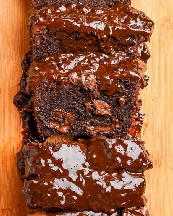 A sliced Ferrero rocher chocolate loaf cake with one slice showing the inside with Nutella and nutty chocolate drizzle on top.