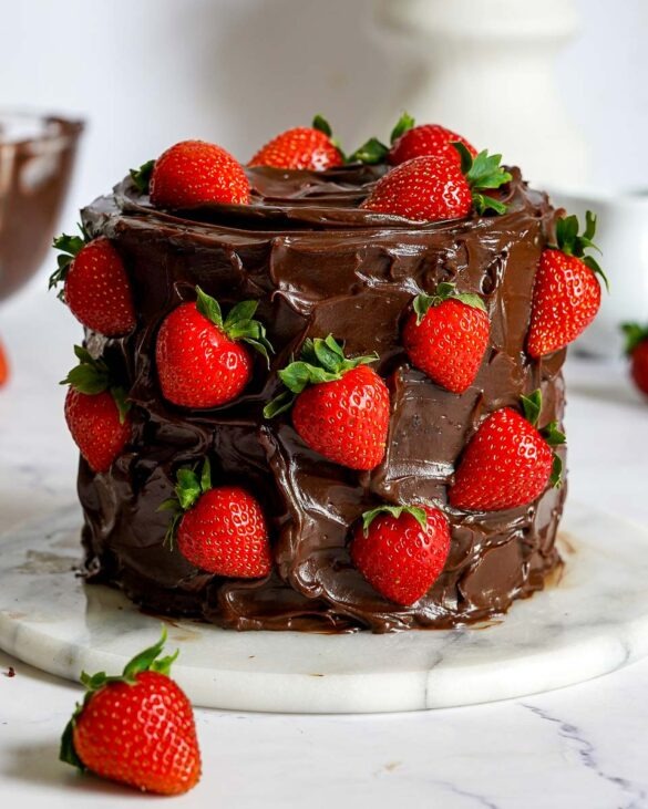 Strawberry Nutella Chocolate Cake covered in a messy chocolate ganache and fresh strawberries.