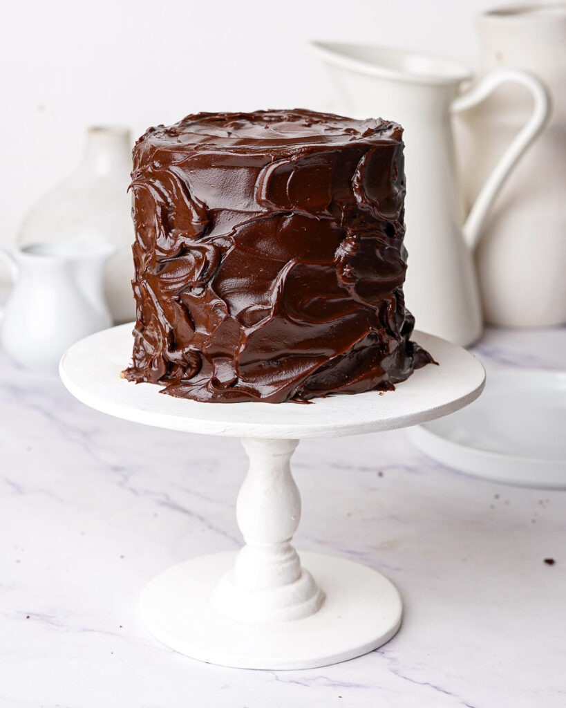 Mini Matilda Chocolate Cake on a cake stand covered in a messy chocolate ganache.