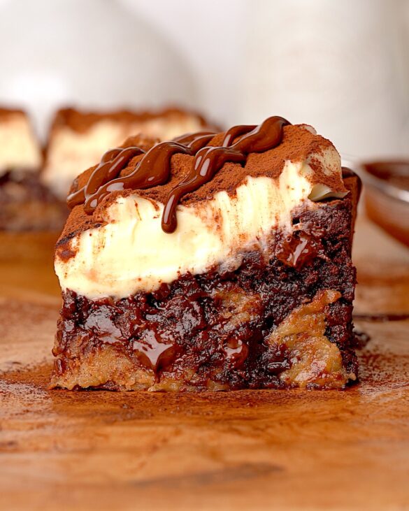Tiramisu Brookies with a layer of Mascarpone cream on top dusted in cocoa with a drizzle of melted chocolate.