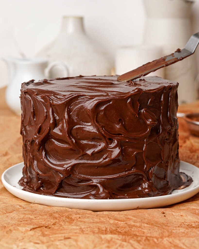 Six ingredient death by chocolate cake covered in a messy chocolate ganache.