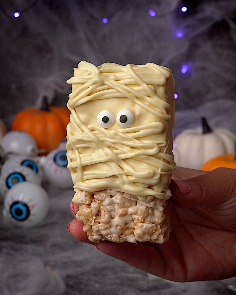 Mummy-rice-krispie-treats-easy-halloween-recipe.jpg - Ems Foodie Fix inished mummy Rice Krispie treats decorated with white chocolate drizzle and candy eyes – easy Halloween dessert idea