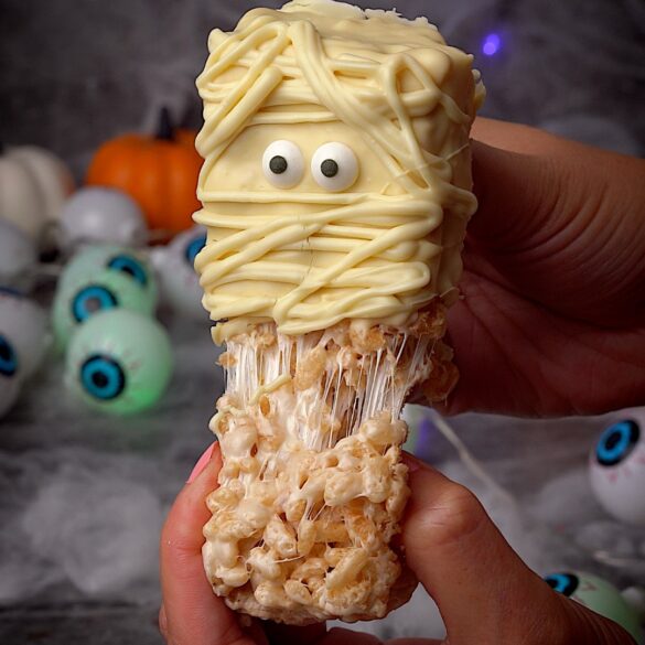 Mummy-rice-krispie-treats-easy-halloween-recipe.jpg “Gooey mummy Rice Krispie treat being pulled apart to show melted marshmallow inside – easy no-bake Halloween dessert.