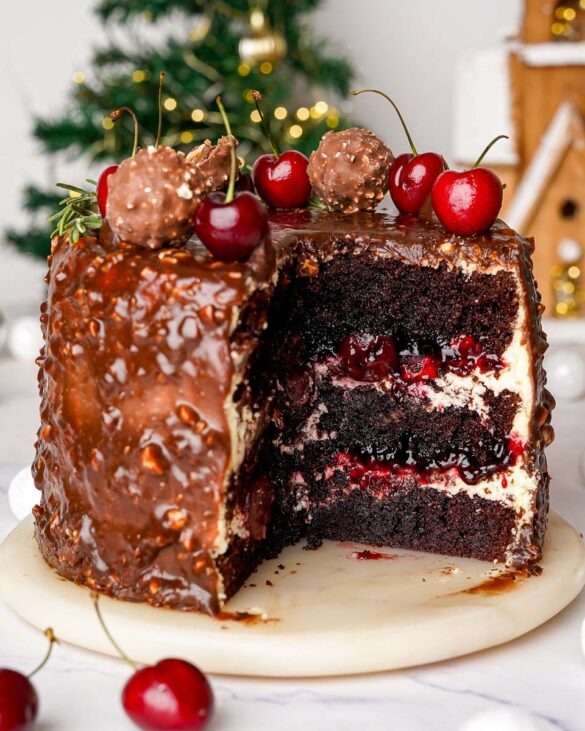 Ferrero rocher black forest cake with a slice removed to reveal the cream and cherry layers inside.
