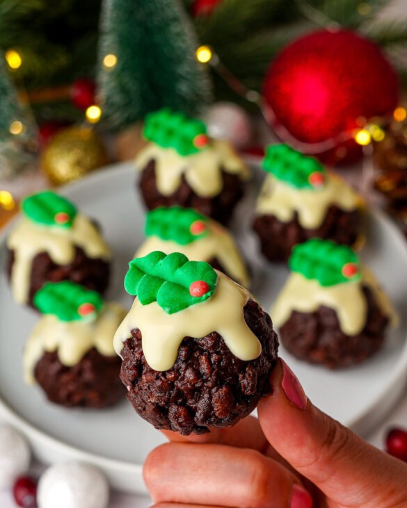 Rice krispie christmas pudding treats with white melted chocolate and a holly decoration on top.