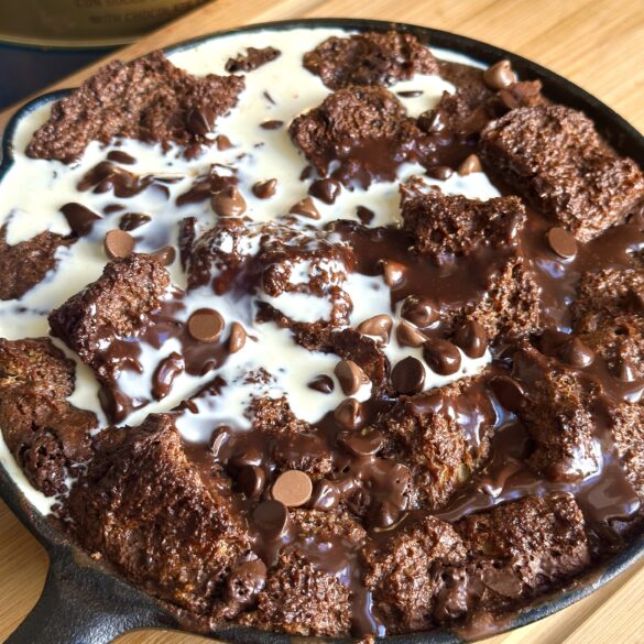 Easy chocolate Pannetone bread pudding in a cast iron skillet with a drizzle of cream on top.