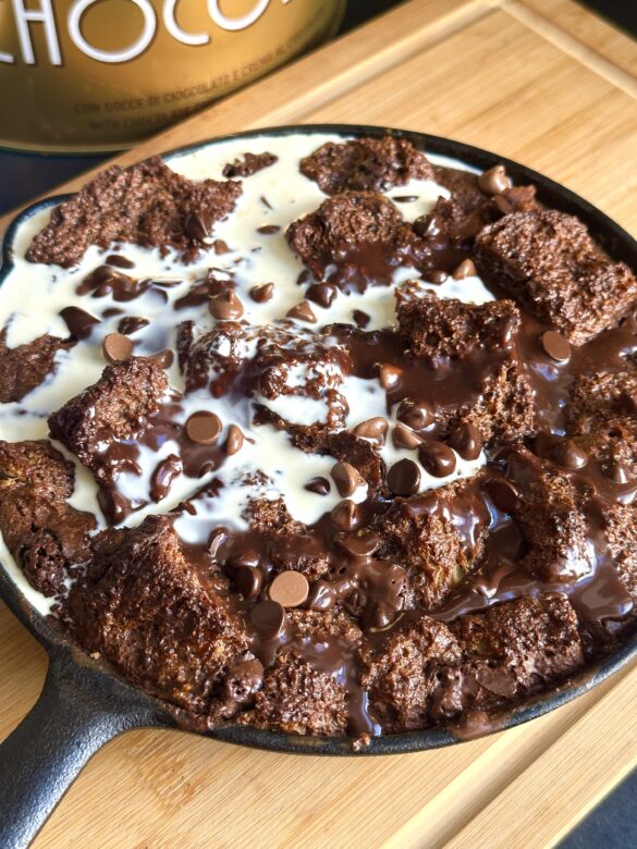 Easy chocolate Pannetone bread pudding in a cast iron skillet with a drizzle of cream on top.