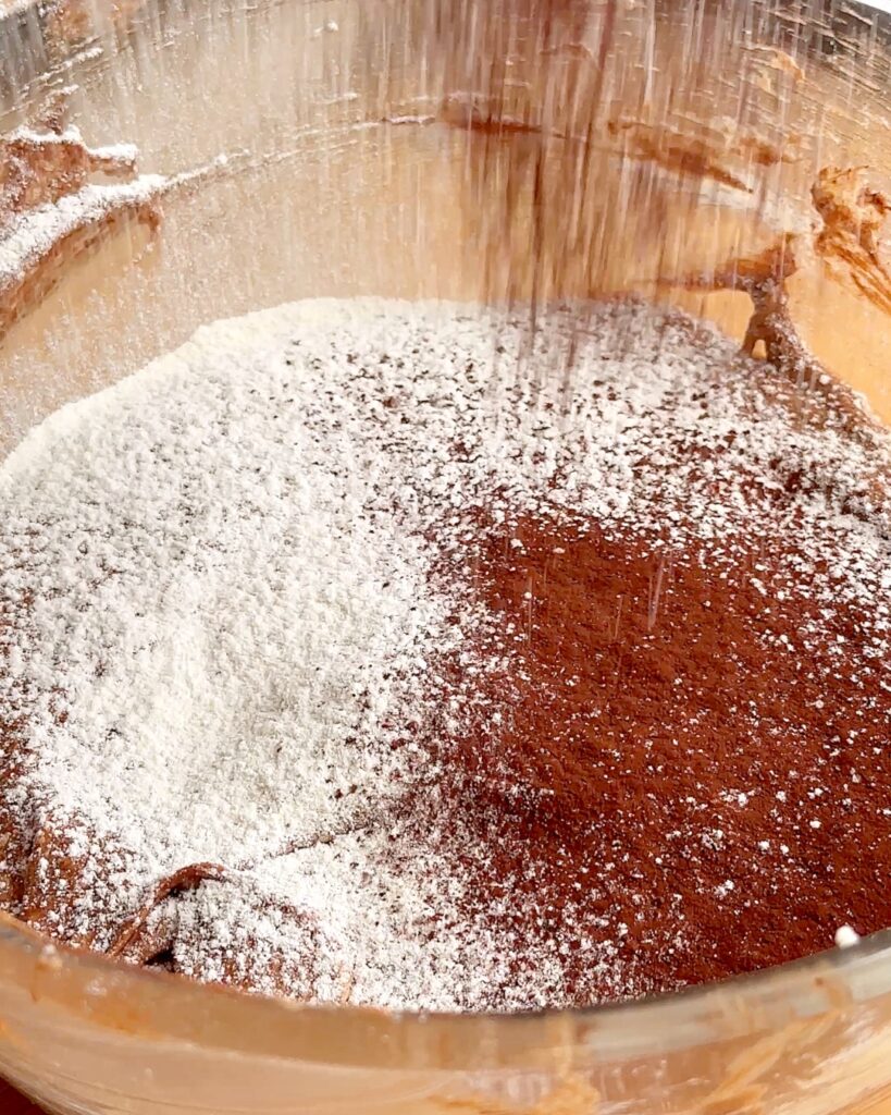 Sifing flour and cocoa into chocolate sponge batter.