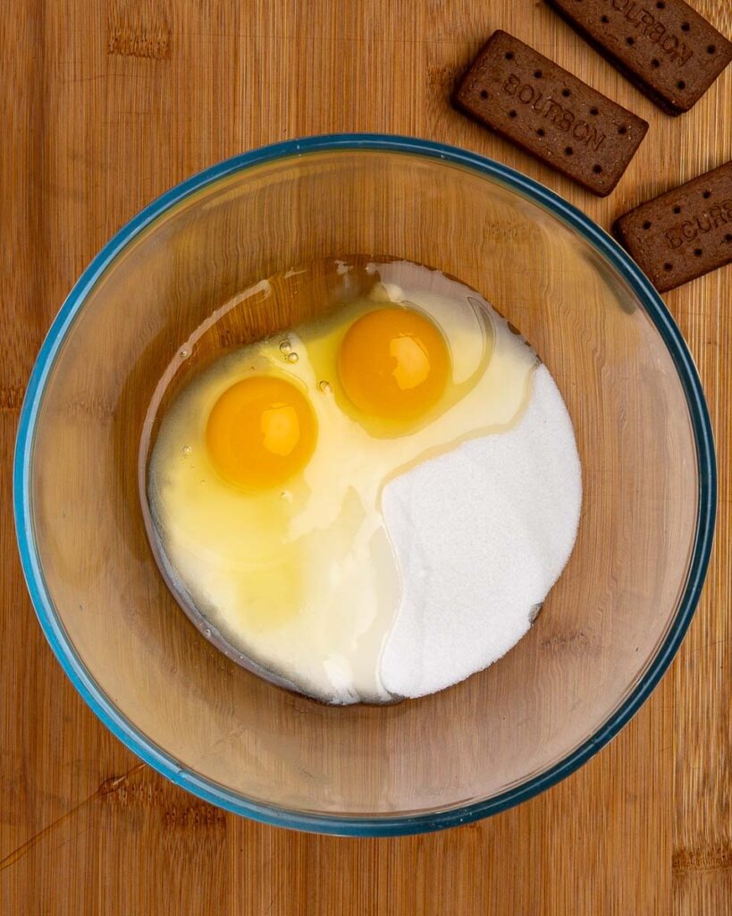 Eggs and sugar in a bowl or fudgy bourbon biscuit brownies.