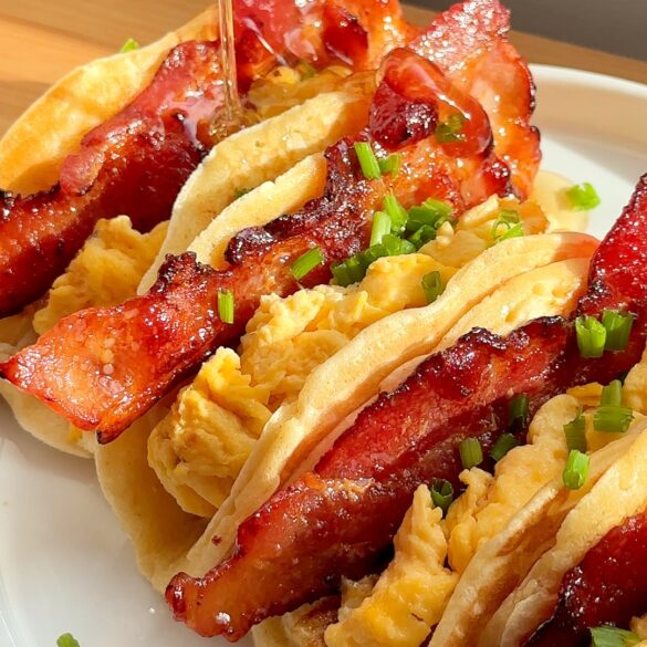 Breakfast Pancake Tacos on a plate with bacon and scrambled eggs inside.