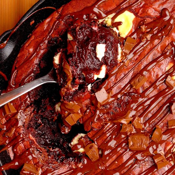 Red-velvet-cheesecake-brownie-skillet.jpg Red velvet cheesecake brownie skillet with a scoop on a spoon.