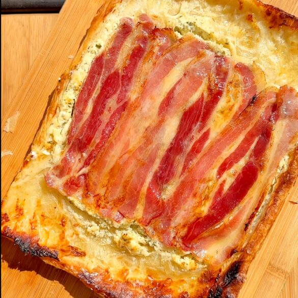 Boursin bacon tart that was baked upside down after its been flipped on a wooden board.