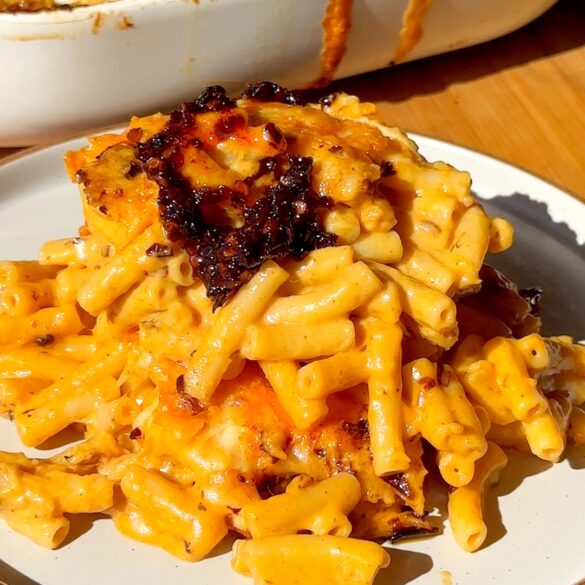 Creamy chiii crisp mac and cheese pasta with orange cheese sauce and a crispy browned topping on a white plate side view.