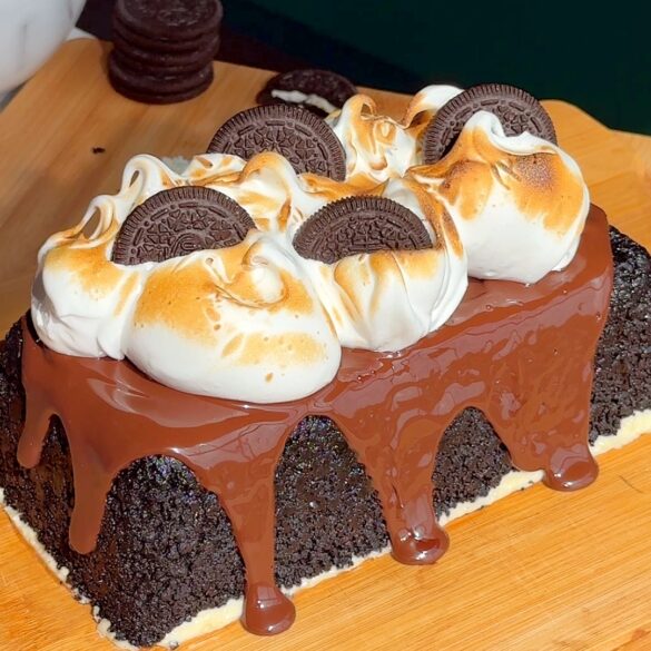 Oreo-upside-down-cheesecake-recipe.jpg Oreo cheesecake on a wooden board with a chocolate glaze dripping down the sides, topped with toasted marshmallow swirls and Oreo cookies on top