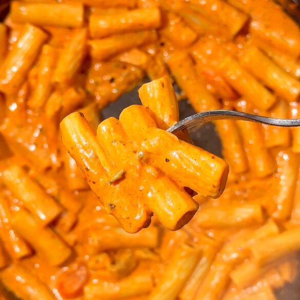 Pesto-vodka-pasta-recipe.jpg Fork lifting orange-coated pestp vodka rigatoni pasta on a fork.