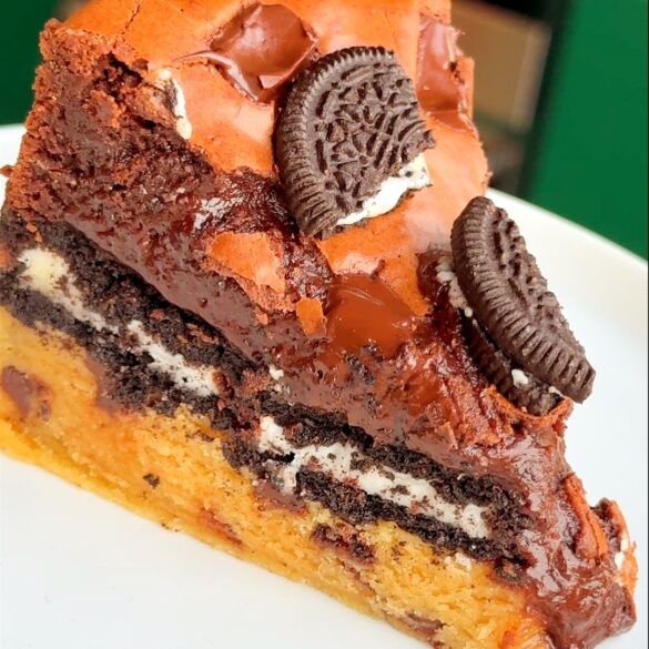 a slice of a slutty brownie pie ona white plate.