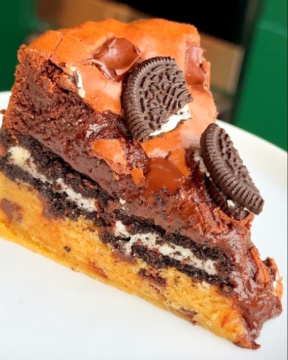 a slice of a slutty brownie pie ona white plate.